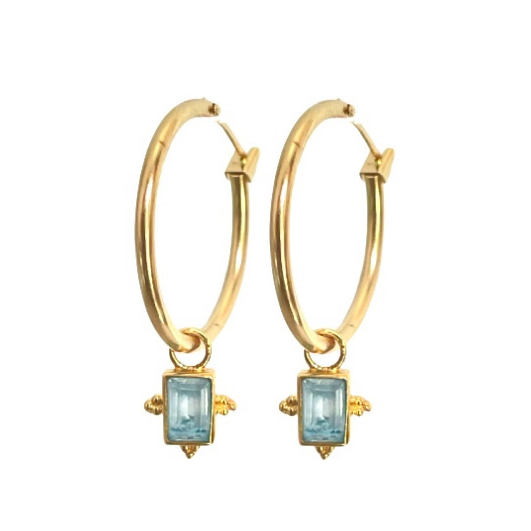 Aros bañadas en oro con colgante en topacio azul por Bechi Ulivi Jewels.
Gold-plated hoops with blue topaz pendants made by Bechi Ulivi Jewels.
